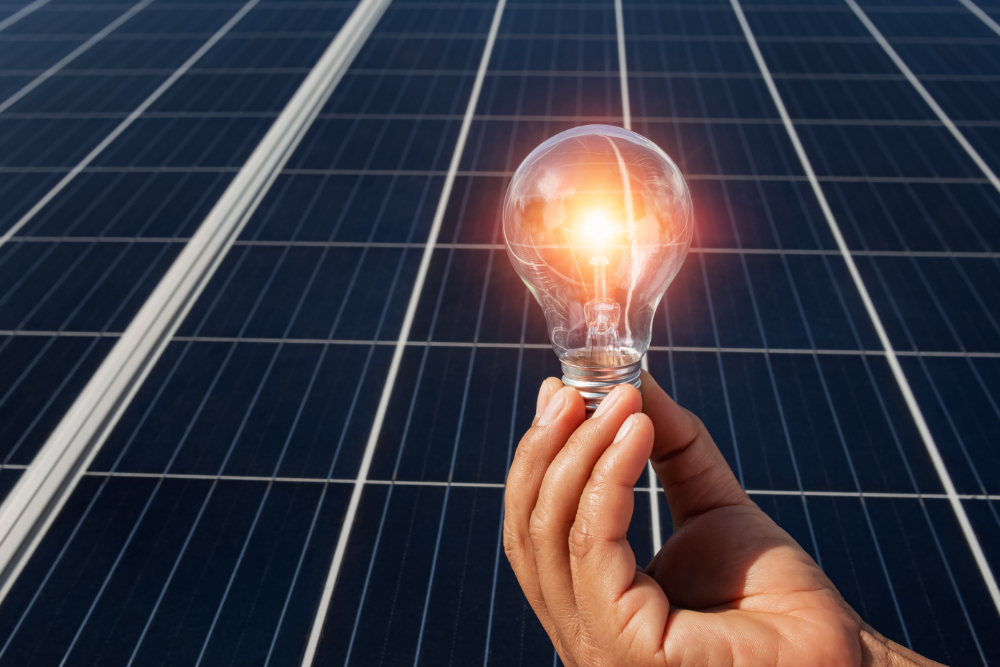 hand holding lightbulb on solar panel concept clean energy in na